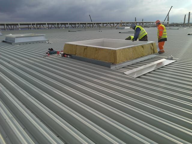 Installers fitting a galvanized steel rooflight footing